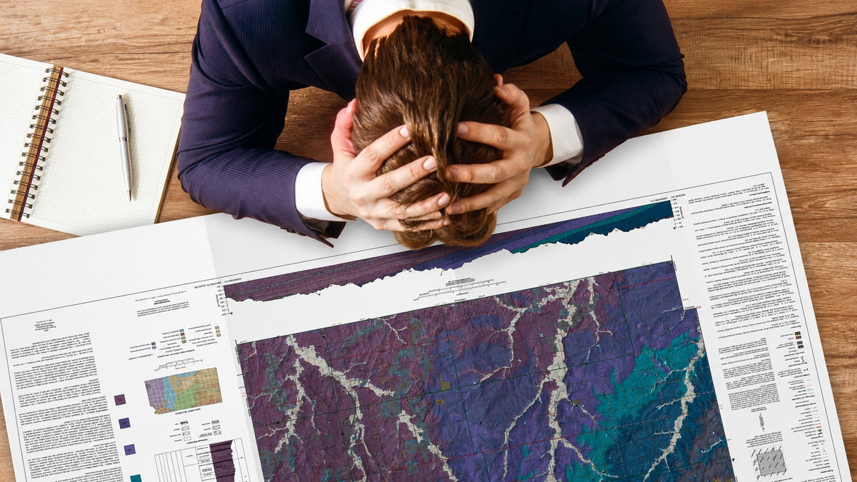 Person reviewing large-format printed plans on a desk, showing how printer problems can slow business print production.